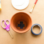 clay pot with blue tape over bottom hole