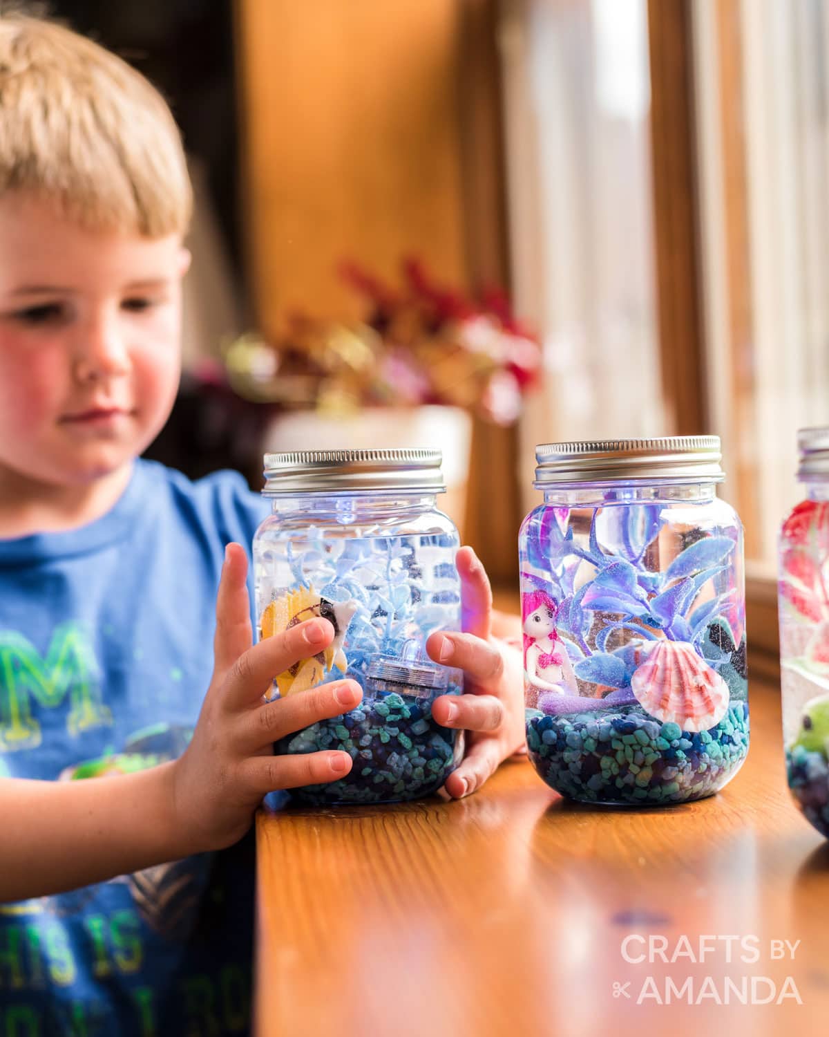 little boy holding mason jar aquarium he made