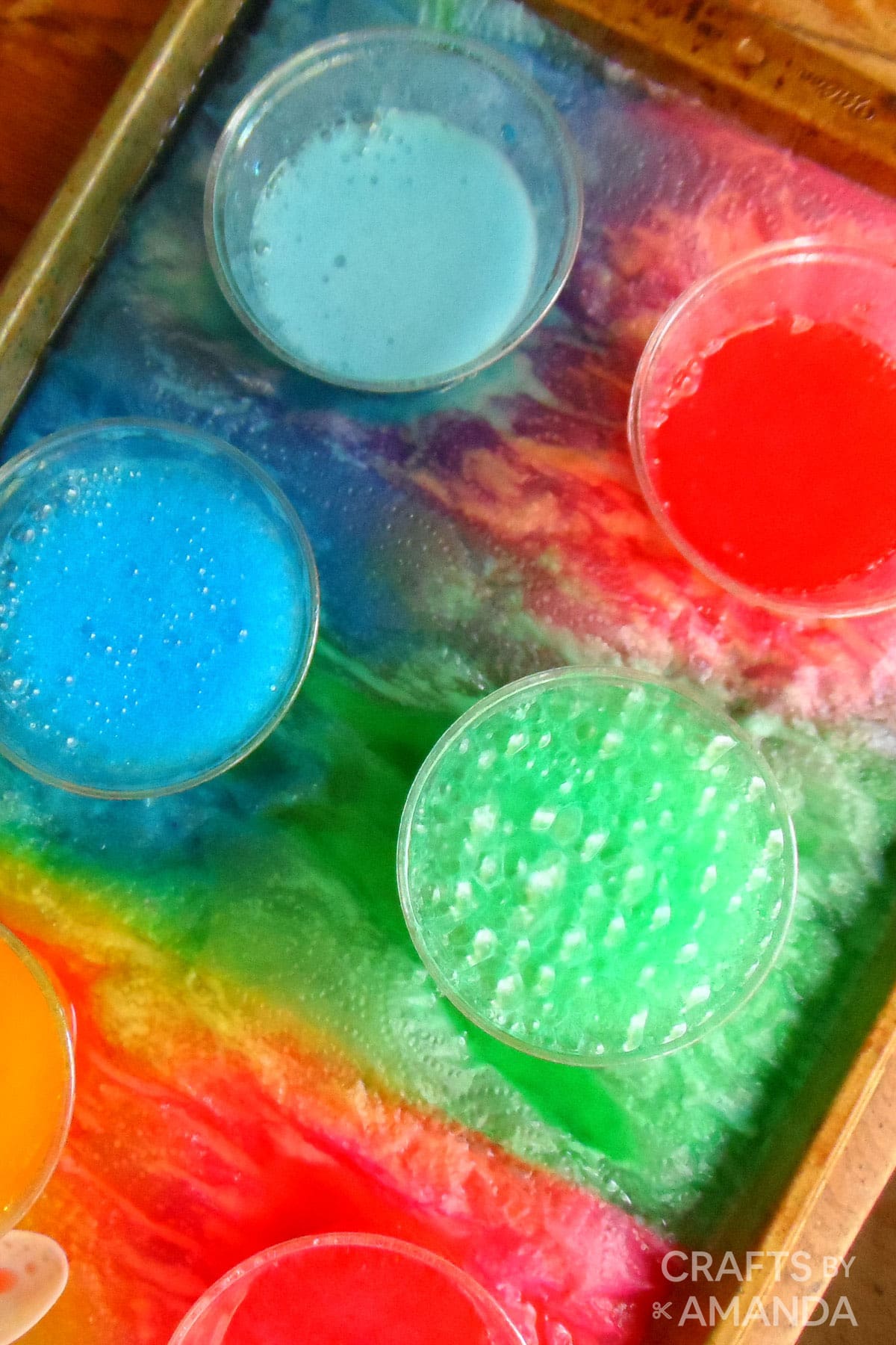 PLASTIC CUPS WITH VINEGAR, BAKING SODA, AND FOOD COLORING ON TRAY