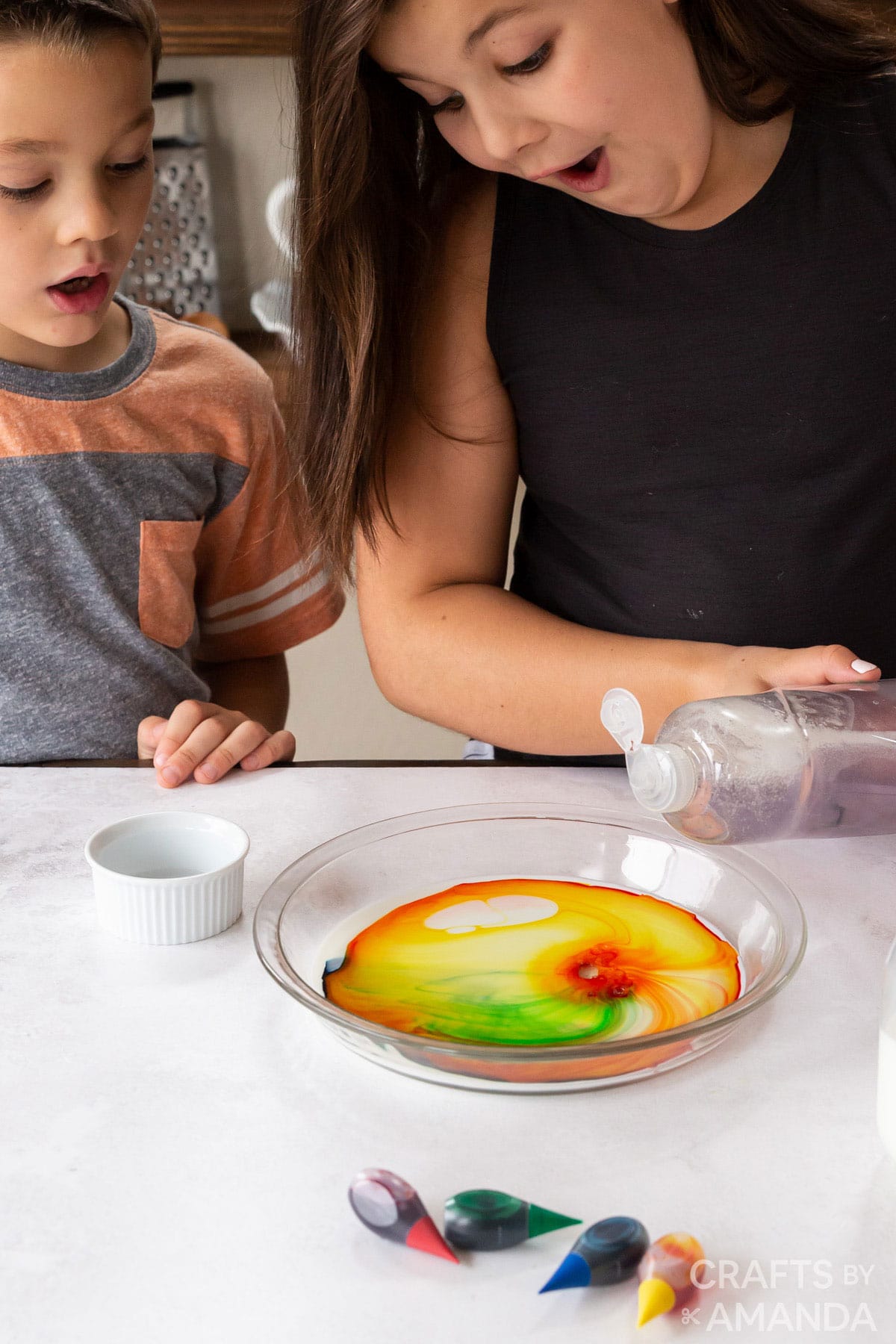 kids adding dish soap to food coloring in milk