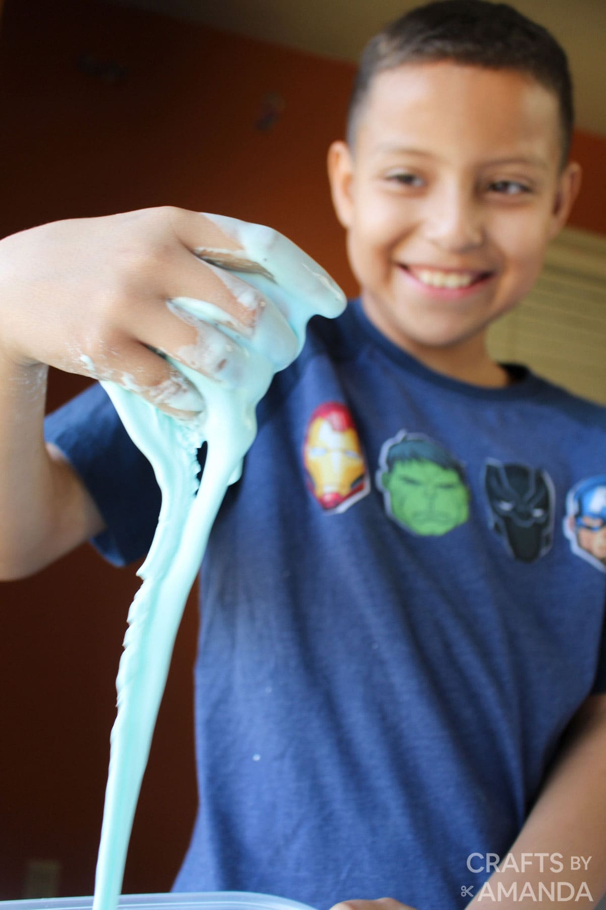 boy smiling and playing with oobleck slime