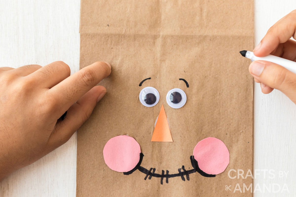 drawing eyebrows on paper bag scarecrow