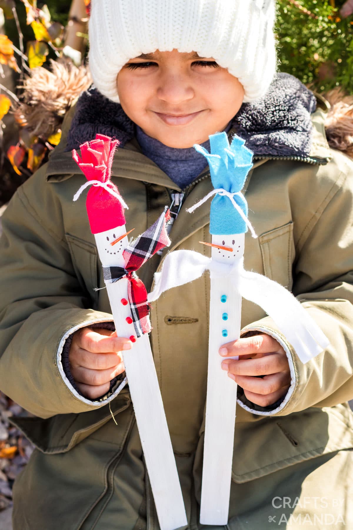 young boy holding paint stick snowmen