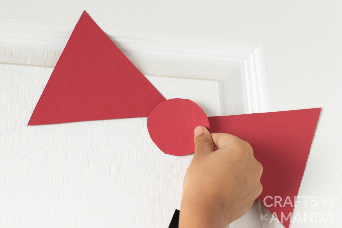 child attaching paper bow to door