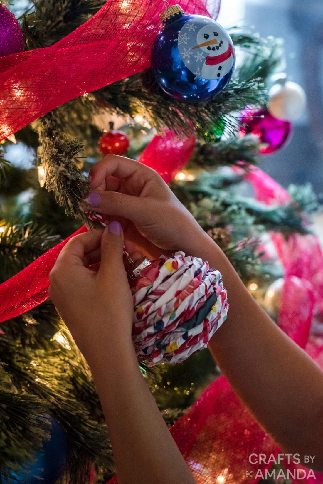 child hanging ornament on tree