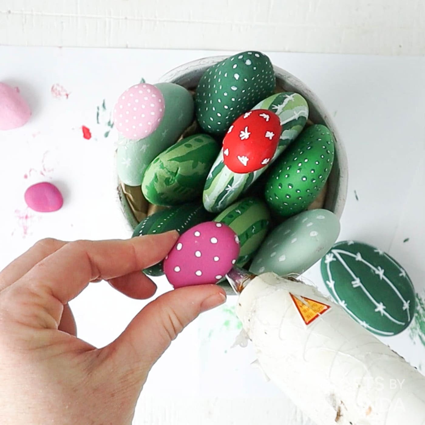 gluing painted rocks into a clay pot