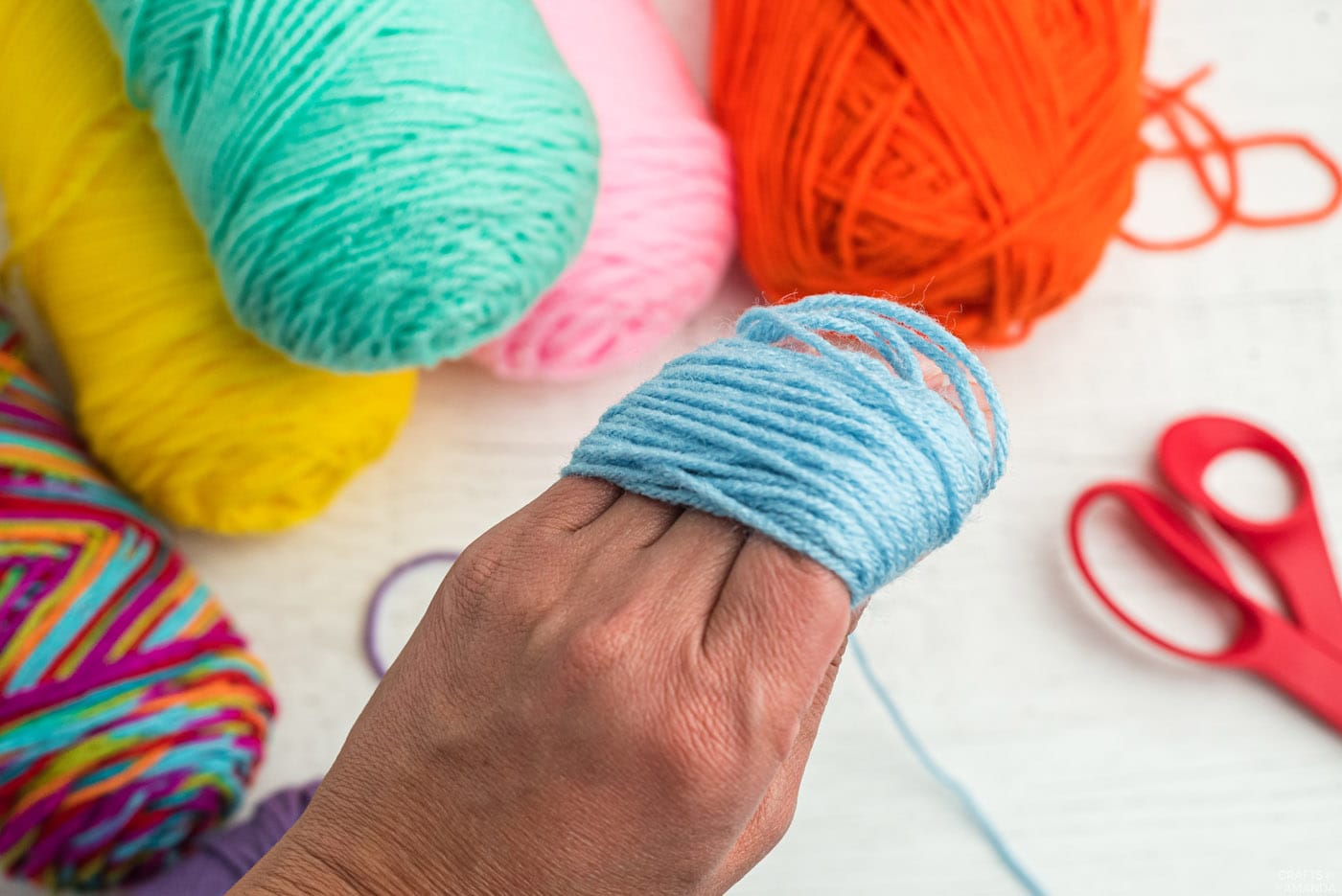 wrapping blue yarn around fingers