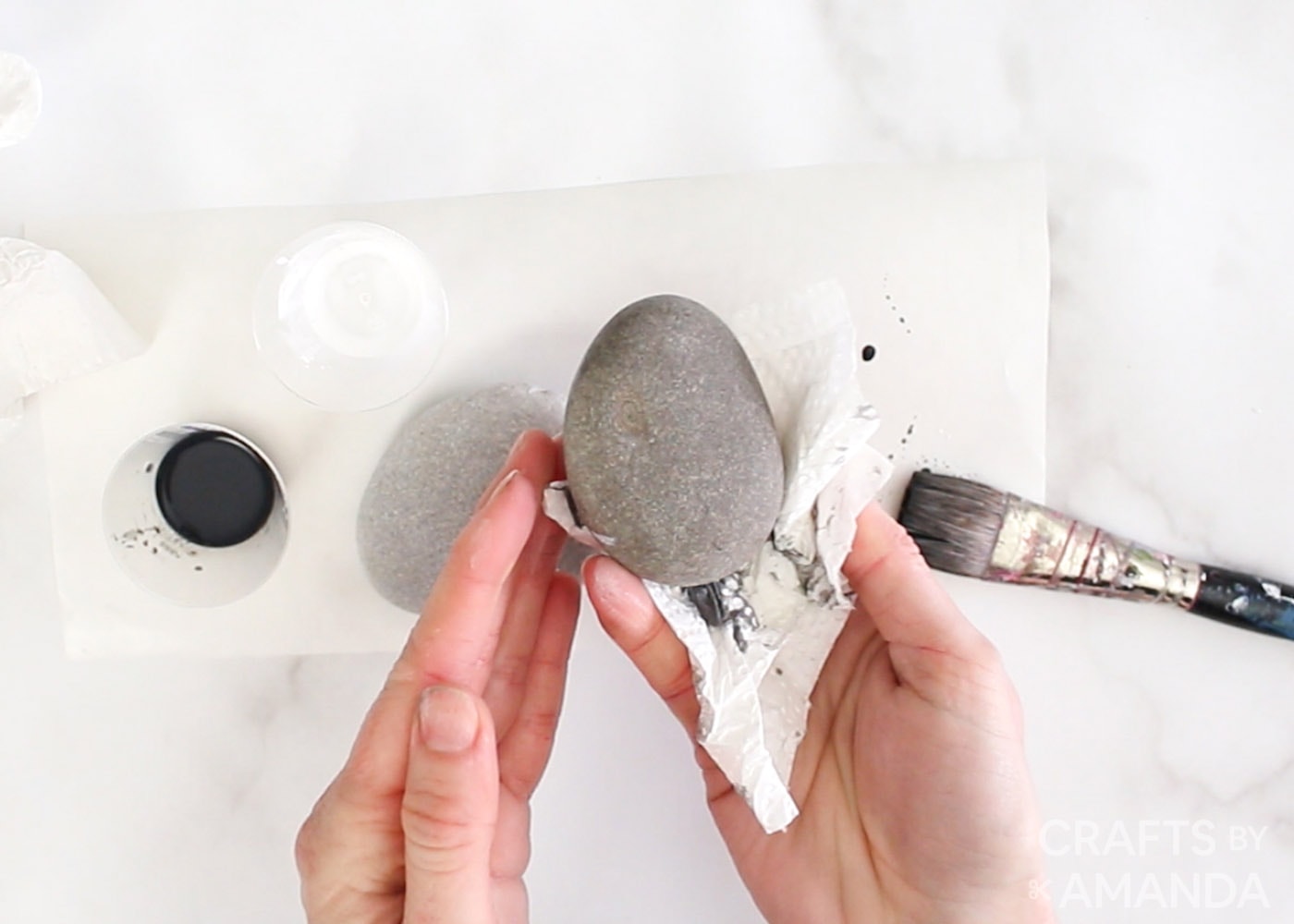 wiping excess paint off rock with a paper towel