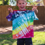 boy holding up shirt he tie dyed