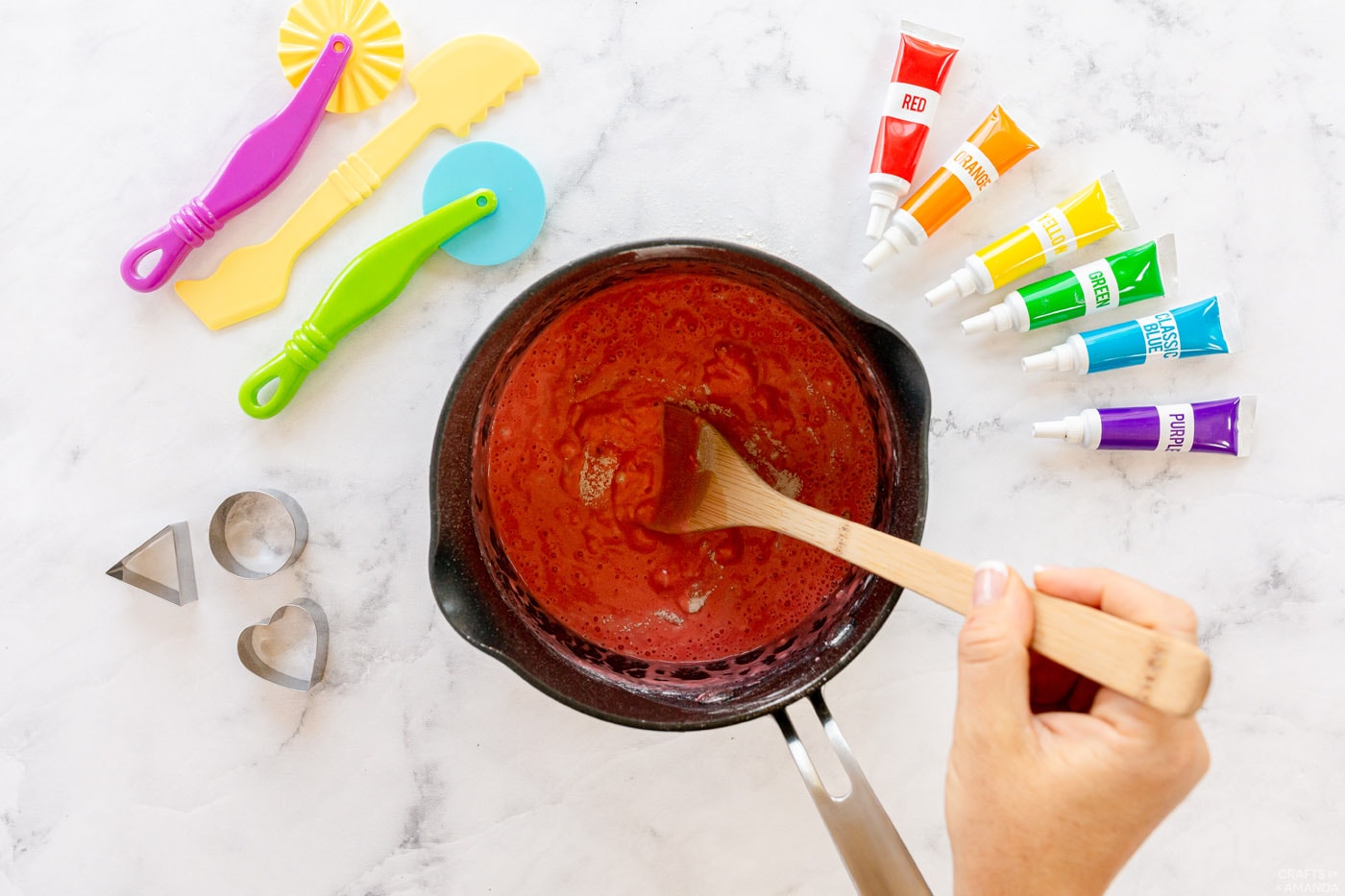 stirring red play dough in a saucepan