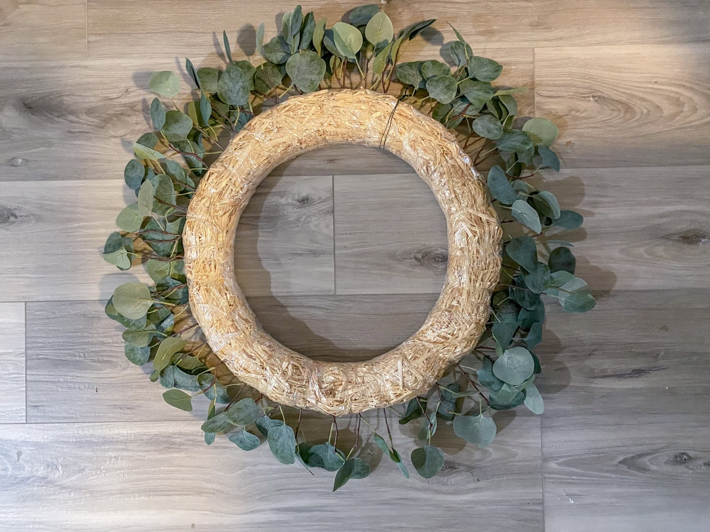perimeter of straw wreath form lined with faux greenery stems