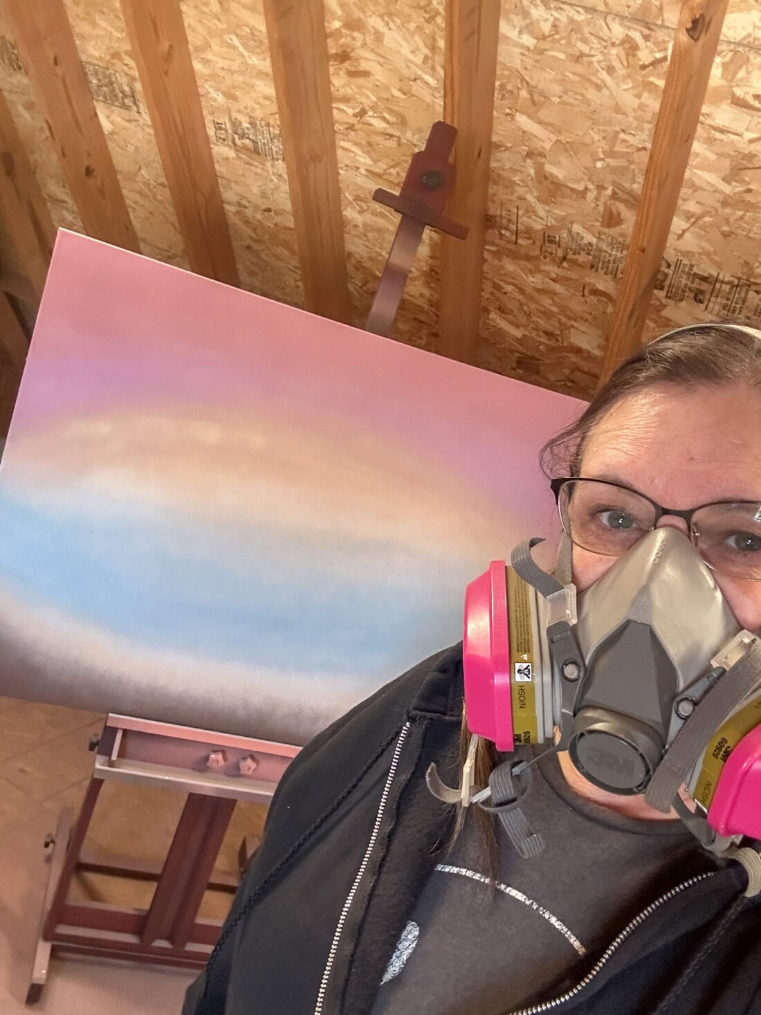 me with a respirator on with my painting in the back