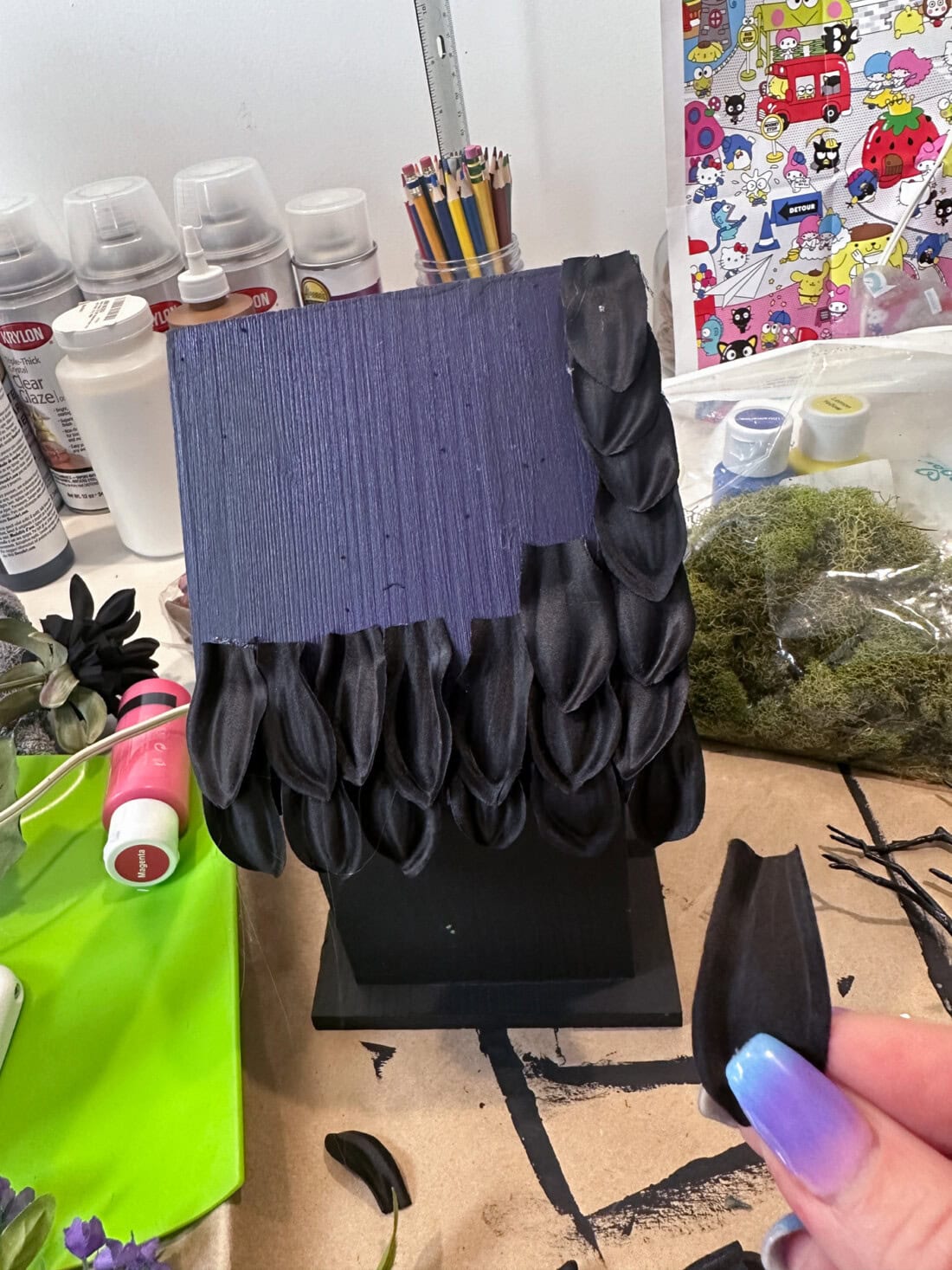 glueing black flower petals to birdhouse roof