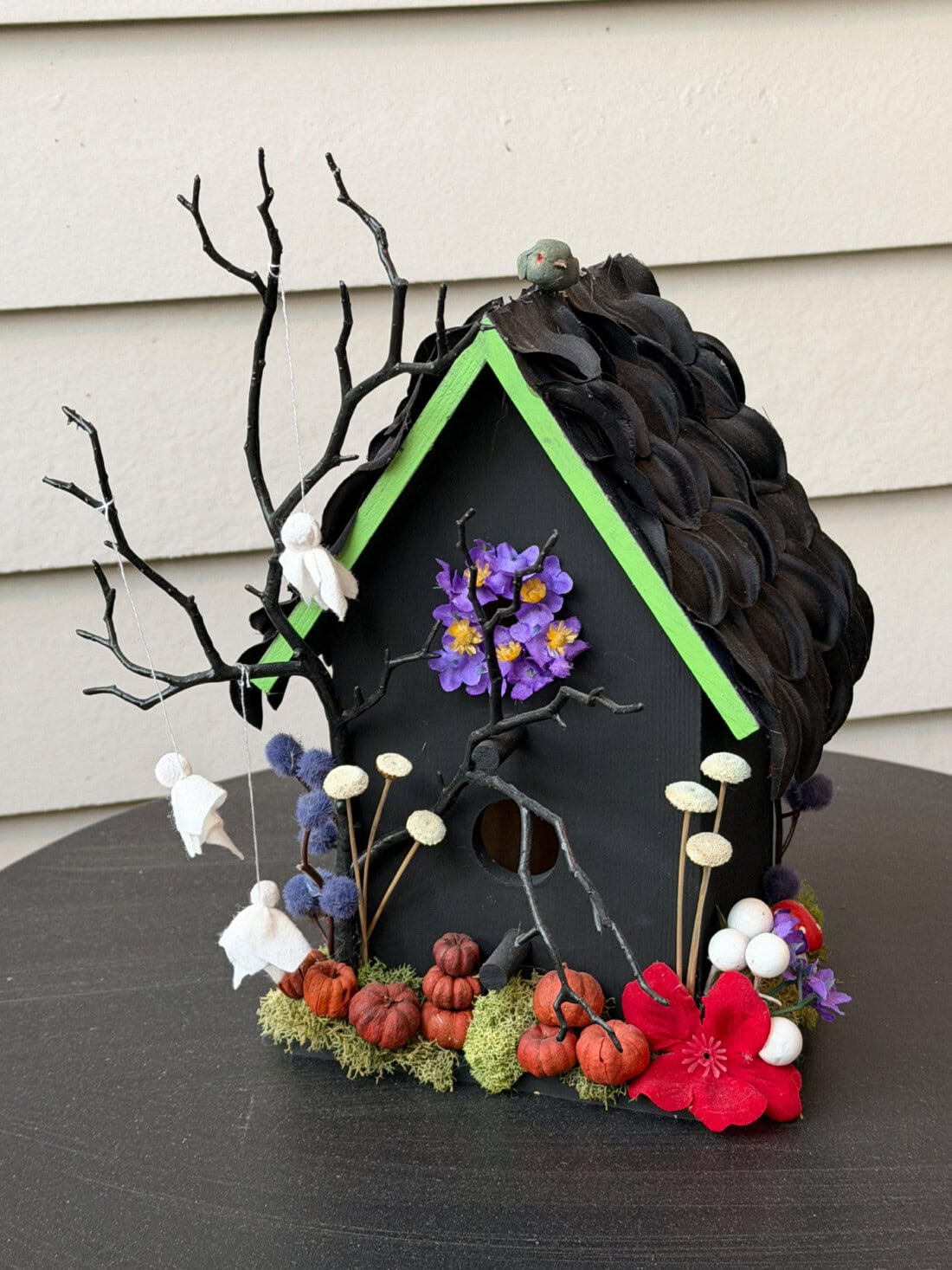 birdhouse painted black and green with halloween themed embellishments